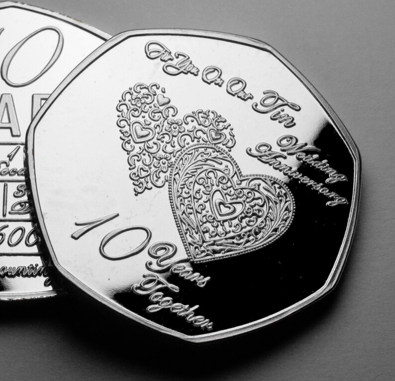 May include: Silver coin with two intertwined hearts and the text "For You Our Tin Wedding Anniversary 10 Years Together".