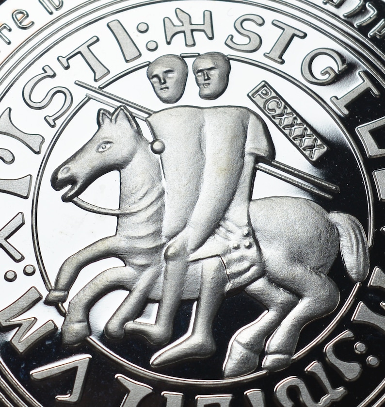 Op de afbeelding: Een zilveren munt met een gedetailleerd beeld van een ridder te paard. De ridder houdt een speer vast en heeft twee hoofden. De munt heeft de tekst "ST:H:STGL" rond de rand.