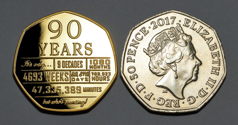 May include: A 50 pence coin commemorating Queen Elizabeth II's 90th birthday. The coin features a portrait of the Queen on one side and a design with the text "90 YEARS" and a breakdown of her reign in decades, months, weeks, days, hours, and minutes on the other side.