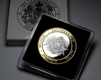 May include: A silver and gold coin with the words "Wisdom, Strength, Brotherhood" around the edge. The coin features a compass and square design with an all-seeing eye in the center.