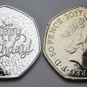以下が含まれることがあります： 2つの銀色の50ペンス硬貨。1つの硬貨には筆記体で「Happy Birthday!」と書かれています。もう1つの硬貨には、エリザベス2世女王の横顔と2017年の年号が描かれています。