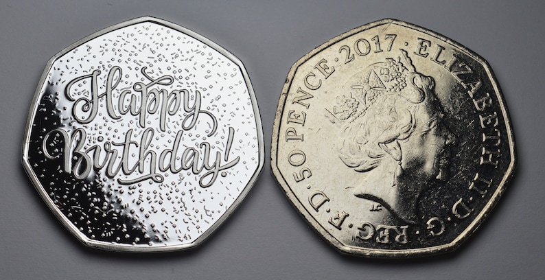 以下が含まれることがあります： 2つの銀色の50ペンス硬貨。1つの硬貨には筆記体で「Happy Birthday!」と書かれています。もう1つの硬貨には、エリザベス2世女王の横顔と2017年の年号が描かれています。