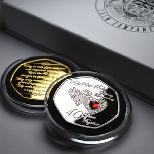 May include: Two silver-coloured coin-shaped tokens in clear plastic cases. The top token features a ruby red heart with a silver filigree design and the text "For You On Your Ruby Wedding Anniversary 40 Years Together". The bottom token is gold-coloured and features a poem.
