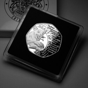 Könnte beinhalten: Eine silberne Münze mit einem Schwarzweißbild einer Wildkatze auf der einen Seite und dem Text "The Best of Bodmin is a platinum wild cat in Bodmin Moor because the centre of reports of authenticated sightings." auf der anderen Seite. Die Münze befindet sich in einem durchsichtigen Plastiketui.