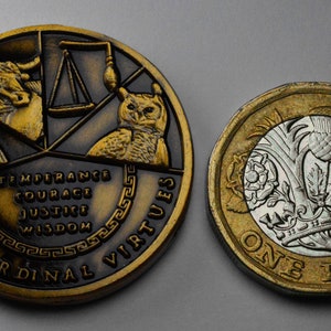 May include: Two gold-colored coins. The larger coin features a bull, scales, and an owl with the text "The Cardinal Virtues" and "Temperance, Courage, Justice, Wisdom". The smaller coin is a British one pound coin with a silver design of a rose, a thistle, and a shamrock.