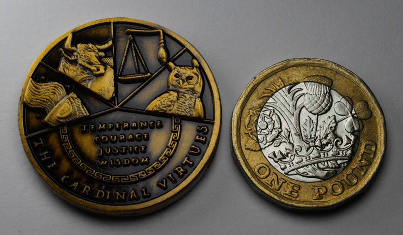 May include: Two gold-colored coins. The larger coin features a bull, scales, and an owl with the text "The Cardinal Virtues" and "Temperance, Courage, Justice, Wisdom". The smaller coin is a British one pound coin with a silver design of a rose, a thistle, and a shamrock.
