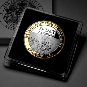 May include: A silver coin with a gold rim commemorating D-Day. The coin features a scene of soldiers landing on the beach and the text "We Shall Fight Them On The Beaches" and "D-Day Landings 6th June 1944".