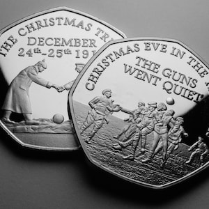 Puede incluir: Dos monedas conmemorativas de plata que representan escenas de la tregua navideña de la Primera Guerra Mundial. La primera moneda muestra a dos soldados dándose la mano, con el texto "The Christmas Truce, December 24th-25th 1914". La segunda moneda muestra a soldados jugando al fútbol, con el texto "Christmas Eve in the Trenches, The Guns Went Quiet".