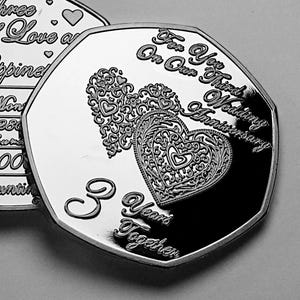 May include: A silver-coloured coin with a decorative heart design and the text "For Your Third Wedding Anniversary On Our Third Anniversary 3 Years Together".