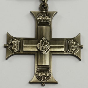 Pu&ograve; includere: Una croce argentata con una corona in alto e in basso e un monogramma reale al centro. La croce &egrave; un elemento decorativo, forse per una medaglia o un premio.