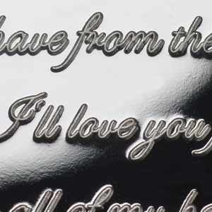May include: Close-up of a silver engraved heart pendant with the inscription "I have from the I'll love you f all of my he"