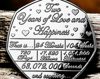 May include: A silver coin inscribed with "Two Years of Love and Happiness" and a breakdown of the time in months, weeks, days, hours, minutes, and seconds. The coin also says "and counting..."