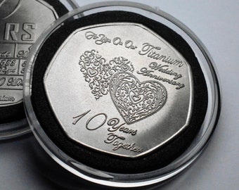 Puede incluir: Una moneda de plata con un respaldo de terciopelo negro en una caja de plástico transparente. La moneda presenta dos corazones entrelazados con diseños intrincados y el texto "For You On Our Titanium Wedding Anniversary 10 Years Together".
