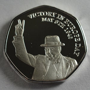 May include: Silver coin commemorating Victory in Europe Day, May 8th, 1945. The coin features a portrait of Winston Churchill raising his hand in a victory salute.