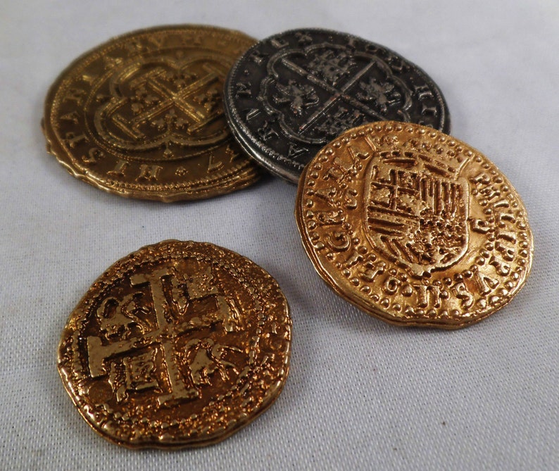 以下が含まれることがあります： 複雑なデザインが施されたアンティークの金貨4枚。十字架、盾、その他の装飾的な要素が特徴です。