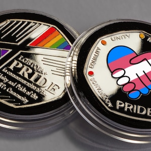 May include: Two silver commemorative coins with a black background. The first coin features a rainbow design and the text "LGBTQ+ PRIDE" with the words "In commemoration of the Unity and Pride of the LGBTQ+ Community". The second coin features a transgender pride flag in the shape of a heart with two hands shaking. The text "PRIDE" is at the bottom of the coin. The words "UNITY", "RESPECT", "BRAVERY", and "VISIBILITY" are around the edge of the coin.