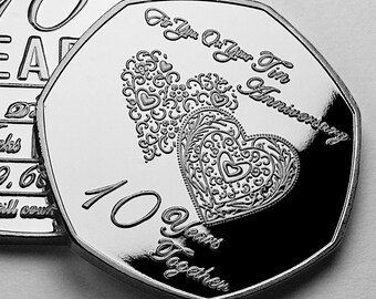 Puede incluir: Una moneda de plata conmemorativa del décimo aniversario. La moneda presenta el texto "Para ti en tu décimo aniversario" y "10 años juntos", con dos corazones ornamentados.