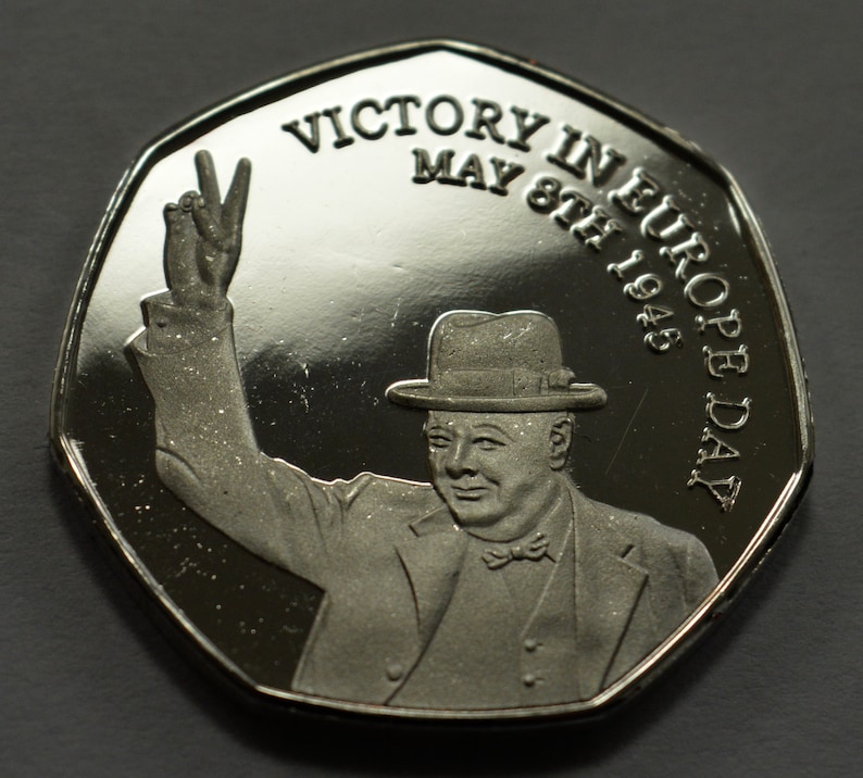 May include: Silver coin commemorating Victory in Europe Day, May 8th, 1945. The coin features a portrait of Winston Churchill raising his hand in victory.