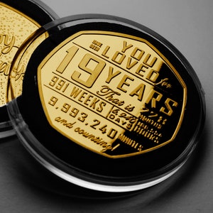May include: A gold-colored coin with the text "You Loved for 19 Years" and the number of weeks, days, hours, and minutes in 19 years. The coin is in a clear plastic case.