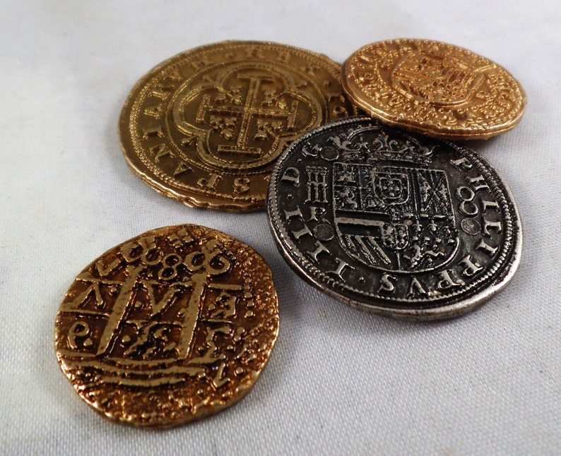 以下が含まれることがあります： 複雑なデザインと文字が刻まれた、金貨2枚と銀貨2枚の計4枚のアンティークコイン。コインは白い表面に並べられています。