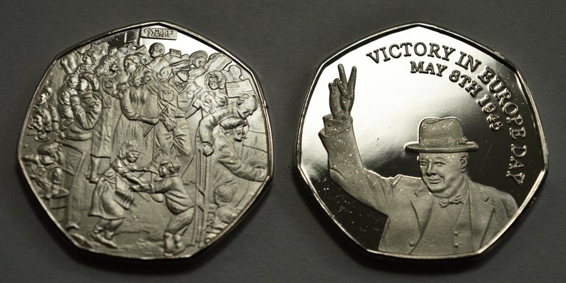 May include: A silver commemorative coin celebrating Victory in Europe Day, May 8th, 1945. One side features a crowd of people celebrating, while the other side shows Winston Churchill giving a victory salute.
