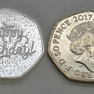 May include: A silver coin with the words "Happy Birthday!" inscribed on one side. The other side of the coin features a portrait of Queen Elizabeth II and the inscription "D.G. REG. F.D. 50 PENCE: 2017 ELIZABETH II.D.C."