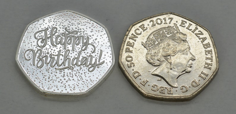May include: A silver coin with the words "Happy Birthday!" inscribed on one side. The other side of the coin features a portrait of Queen Elizabeth II and the inscription "D.G. REG. F.D. 50 PENCE: 2017 ELIZABETH II.D.C."