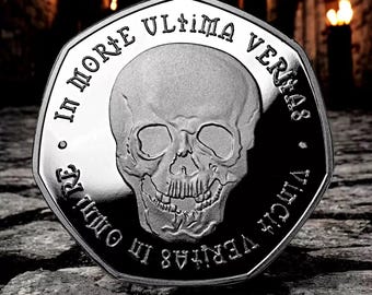 Op de afbeelding: Een zilveren munt met een schedelontwerp en de inscriptie "IN MORTE ULTIMA VERITAS" rond de rand.