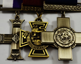 May include: Three gold and silver medals with a red, white, and purple ribbon. The medals are all crosses with different designs. The first medal is a silver cross with a crown on each end and the letters "G.R." in the center. The second medal is a gold cross with a lion and the words "For Valour" on the rim. The third medal is a silver cross with a knight on horseback and the words "For Gallantry" on the rim.