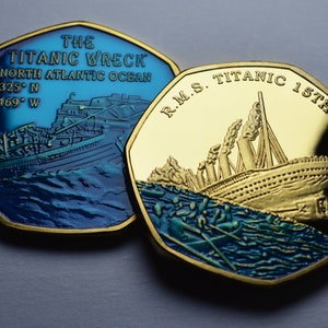 Może przedstawiać: Dwie złote monety z wizerunkami Titanica. Jedna moneta przedstawia wrak statku z napisem "THE TITANIC WRECK NORTH ATLANTIC OCEAN" i współrzędnymi. Druga moneta przedstawia statek na wodzie z napisem "R.M.S. TITANIC 15TH APRIL 1912".