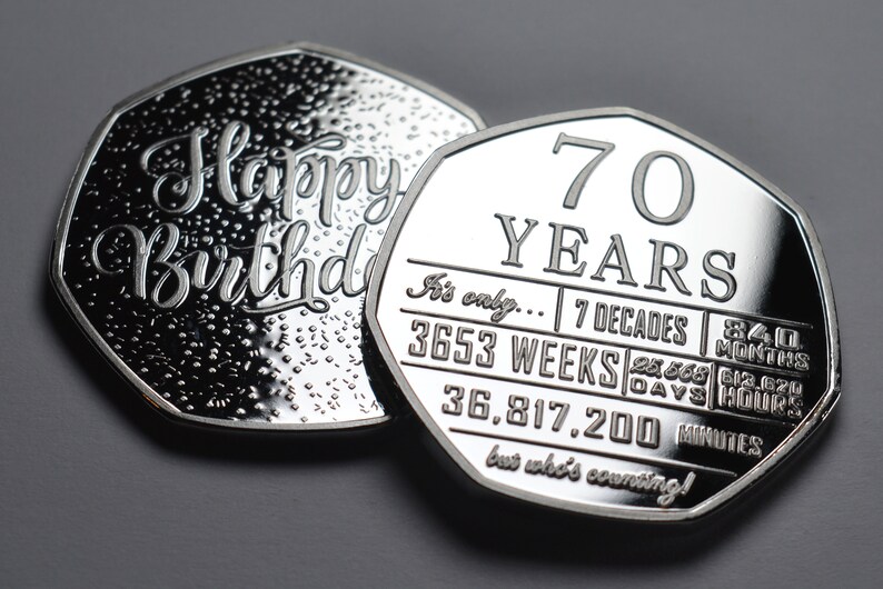 May include: Two silver-colored coins with a decorative design. One coin says "Happy Birthday" and the other coin says "70 Years" and lists the number of weeks, days, hours, and minutes in 70 years.