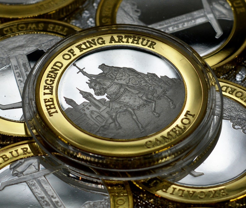 May include: A silver coin with a gold rim featuring a depiction of King Arthur and the legend "The Legend of King Arthur Camelot".