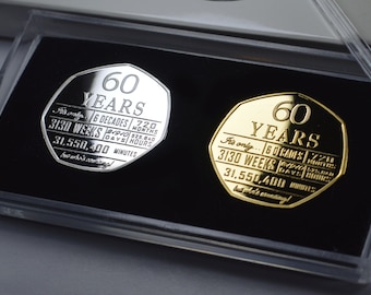 May include: Two commemorative coins, one silver and one gold, displayed in clear plastic cases. Each coin features the text "60 YEARS" and calculations of time, including weeks, days, and minutes. The coins are set against a black background.