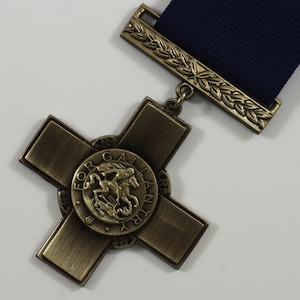 Pu&ograve; includere: Una medaglia di bronzo a forma di croce con un design circolare al centro. Il design presenta un cavallo e un cavaliere con le parole "For Gallantry" incise attorno al bordo.