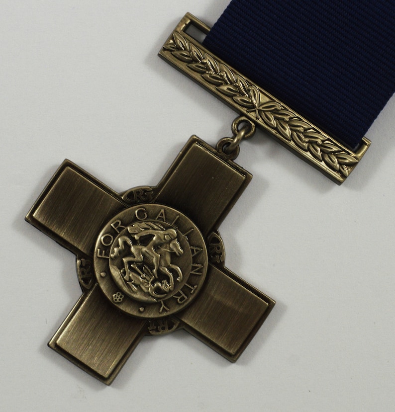 Pu&ograve; includere: Una medaglia di bronzo a forma di croce con un design circolare al centro. Il design presenta un cavallo e un cavaliere con le parole "For Gallantry" incise attorno al bordo.