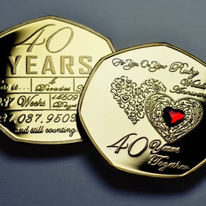 Op de afbeelding: Twee gouden munten ter herdenking van een 40-jarig jubileum. De ene munt heeft de inscriptie "40 JAAR" en de andere munt heeft een robijnrood hart met de inscriptie "Voor U Op Uw Robijnrode Huwelijksjubileum 40 Jaar Samen".