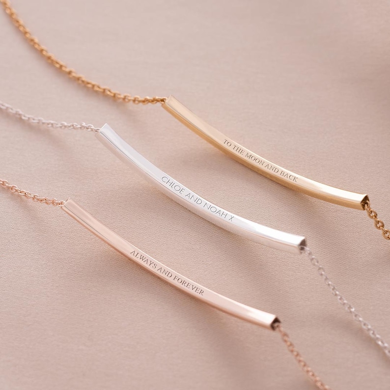 Three curved skinny bar bracelets with text engraved. One in rose gold, one silver, gold.