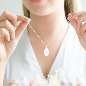 Model holding a Sterling Silver Oval Birth Flower Personalised Necklace