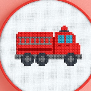 May include: A red fire engine cross stitch pattern in a white embroidery hoop. The truck has a ladder on the side and a blue window.