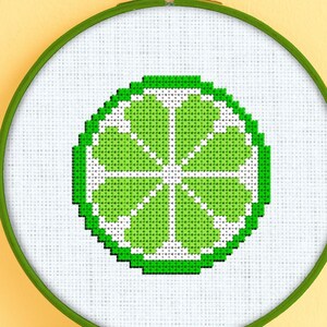 May include: A green lime cross-stitch pattern in a white embroidery hoop with a wooden frame.