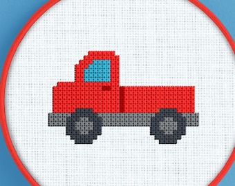 Può includere: Un telaio da ricamo a punto croce con un camioncino rosso con ruote nere e una finestra blu. Il camion è centrato su tessuto bianco, incorniciato da un cerchio rosso. Lo sfondo è blu.