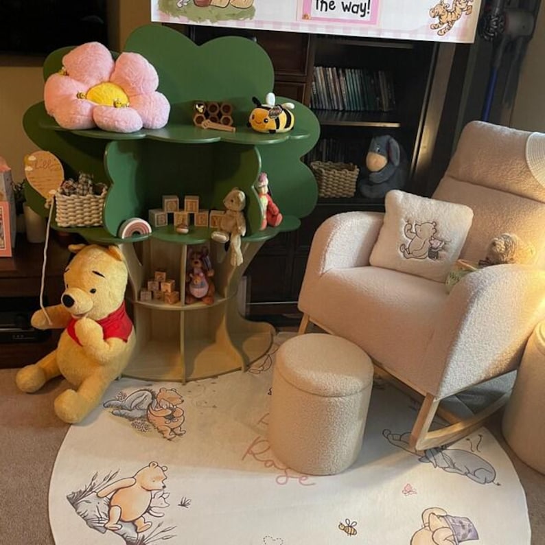 May include: A nursery scene with a green tree-shaped shelf holding toys, a Winnie the Pooh plush, and a pink flower. A cream rocking chair and ottoman are on a round rug with Winnie the Pooh illustrations. The scene is designed for a child's room.