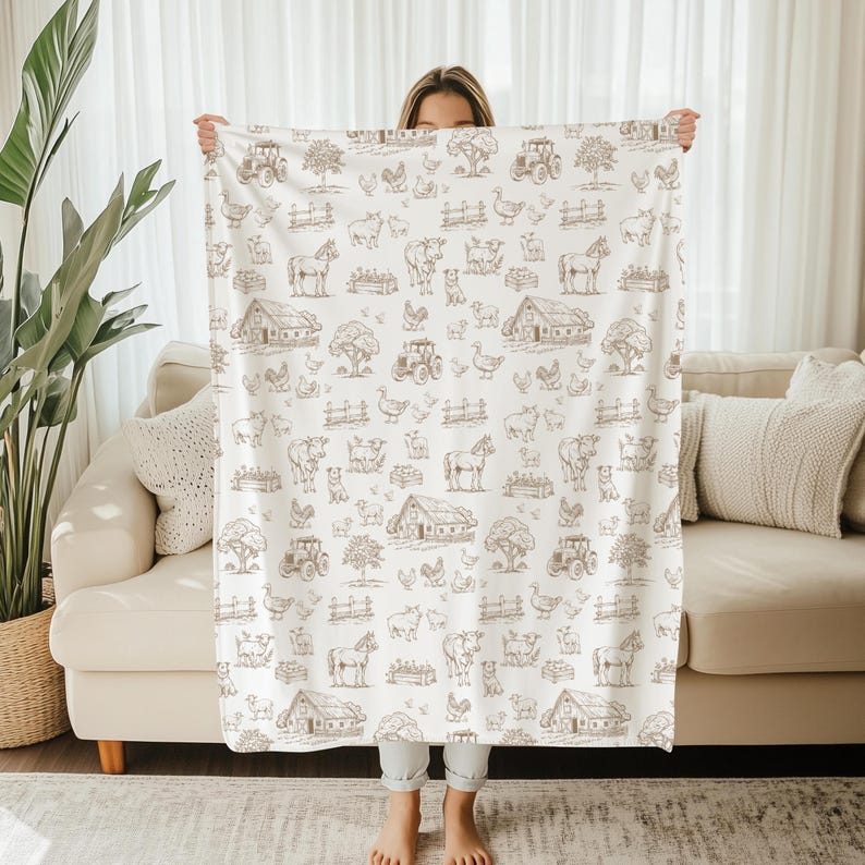 May include: A white throw blanket featuring a repeating brown line-art pattern of farm scenes, including barns, tractors, horses, cows, sheep, chickens, and trees. The design is evenly distributed across the fabric in a grid-like arrangement.