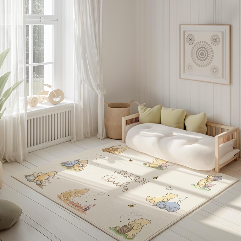 May include: A cream-coloured rectangular rug featuring cartoon illustrations of Winnie the Pooh characters. The rug has the names "Jackson" and "Charles" printed on it. The room also includes a wooden daybed, pillows, and a framed artwork.