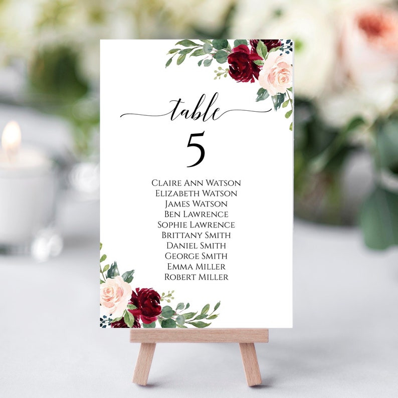 May include: Table number 5 with burgundy and blush floral design. The names Claire Ann Watson, Elizabeth Watson, James Watson, Ben Lawrence, Sophie Lawrence, Brittany Smith, Daniel Smith, George Smith, Emma Miller, and Robert Miller are listed below the table number.