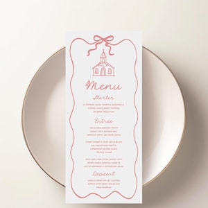 Può includere: Un menu di nozze con un'illustrazione di chiesa rosa e un fiocco in alto. Il menu elenca antipasti, piatti principali e dessert. La carta è su un piatto bianco con bordo dorato.