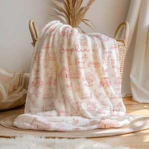May include: A cream-colored fleece blanket featuring a repeating red line-art pattern of farm animals, tractors, barns, and trees. The name Sophia is printed in a cursive red script in the center of the blanket fabric.