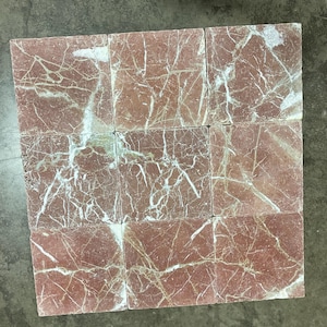 May include: Nine square tiles made of red marble with white veining. The tiles are arranged in a 3x3 grid.