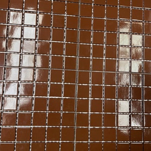 May include: A sheet of brown glossy square tiles with a grid pattern. The tiles are arranged in rows and columns.