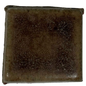 May include: A rectangular bar of dark brown soap with a rough, textured surface.